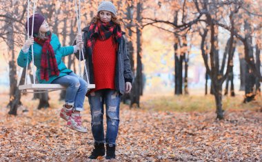 Kız sonbahar şehir parkında yaprak düşer. Genç güzel wi anne