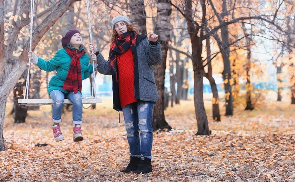 Chica en otoño parque de la ciudad en otoño de hojas. Joven hermosa madre wi — Foto de Stock