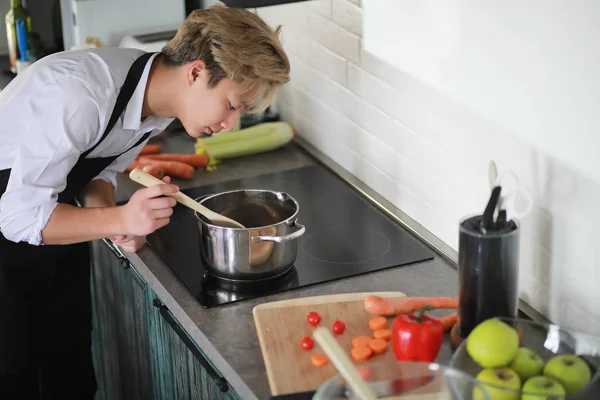 Asian cook in the kitchen prepares food in a cook suit