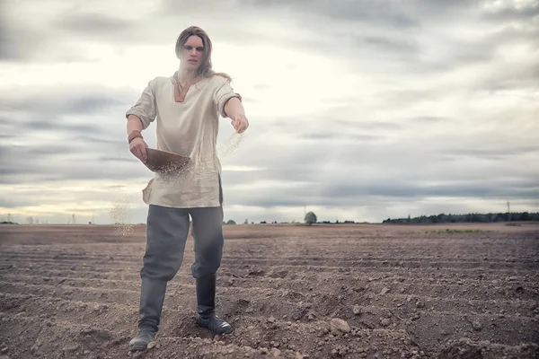 A young peasant sows the field with grain — Stock Photo, Image