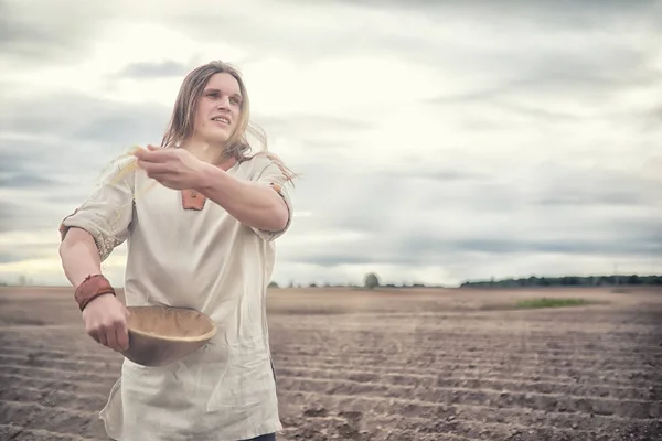 A young peasant sows the field with grain — Stock Photo, Image