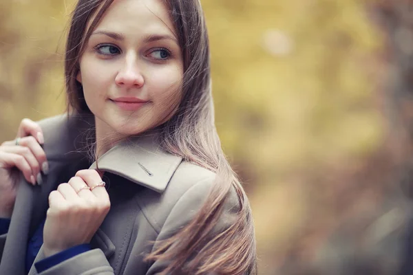 Chica joven en un abrigo en el parque de otoño —  Fotos de Stock