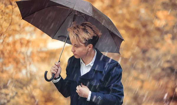 Herbstliches Regenwetter und ein junger Mann mit Regenschirm — Stockfoto