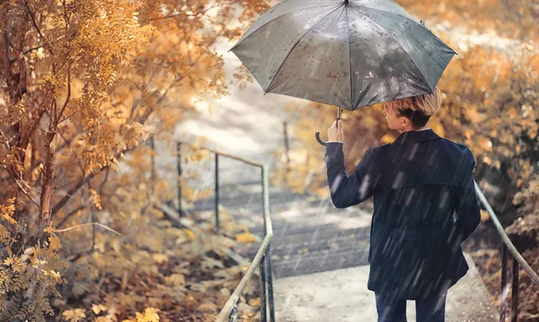 Autunno tempo piovoso e un giovane uomo con un ombrello — Foto Stock