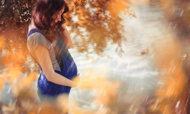 Hamile bir kadın parkta yürüyor.