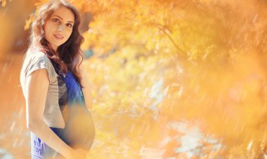 Hamile bir kadın parkta yürüyor.