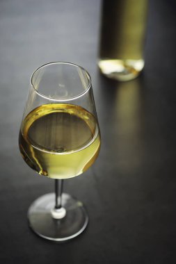 Masada şeffaf beyaz kuru şarap şişesi. Ahşap bir duvar arka plan üzerinde beyaz şarap cam.