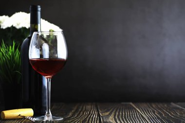 Masada bir bardak kırmızı şarap. Siyah şişe ve bir bardak şarap..