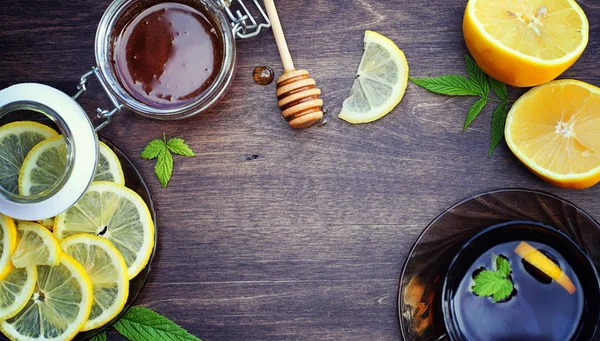 Honey and lemon. Honey stick and slices of sliced lemon on wooden table. Tea in a cup and sweet lime honey in a jar