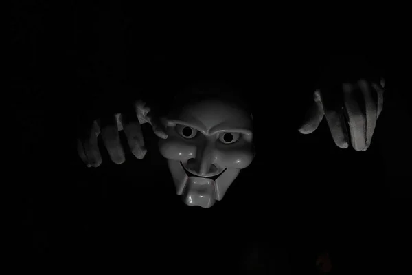 White scary mask on a black background with whites hand. — Stock Photo, Image