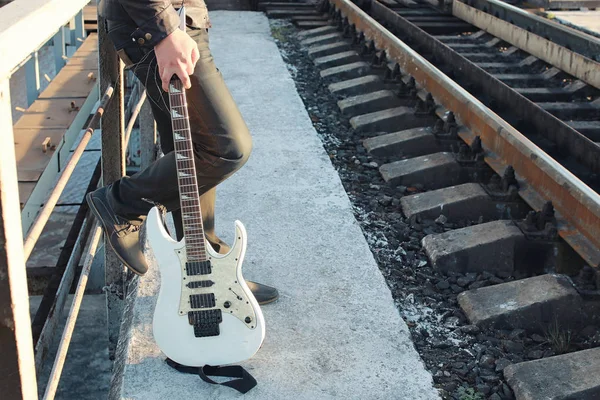 Hombre con una guitarra eléctrica en el paisaje industrial al aire libre — Foto de Stock