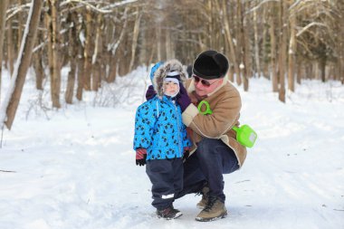 Ailesi olan bir çocuk kış parkında eğleniyor.