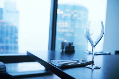 Pencere kenarında uzun bir binanın camının yanında kokteyl bardakları.