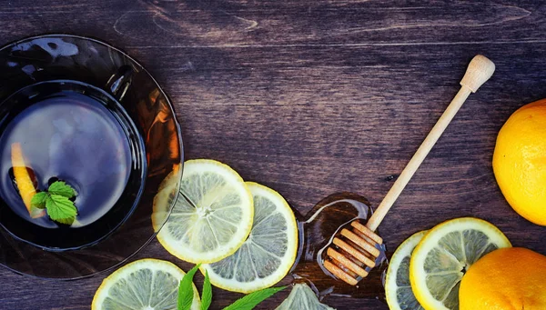 Honey and lemon. Honey stick and slices of sliced lemon on wooden table. Tea in a cup and sweet lime honey in a jar