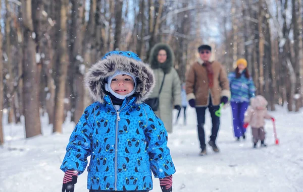 Малюк грає в зимовому парку і розважається з сім'єю — стокове фото
