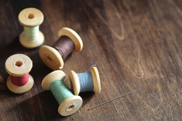 Hilo de coser sobre un fondo de madera. Juego de hilos en bobinas — Foto de Stock