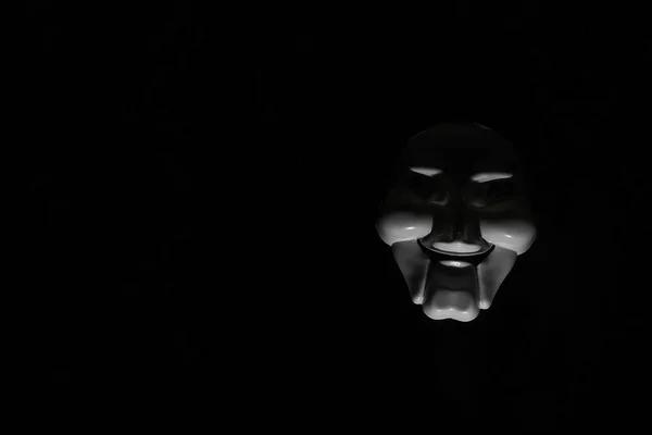 Λευκή τρομακτική μάσκα σε μαύρο φόντο με λευκό χέρι. — Φωτογραφία Αρχείου