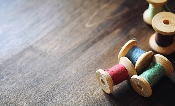 Filo da cucire su uno sfondo di legno. Set di fili su bobine — Foto Stock