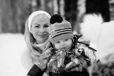 Genç bir anne kucağında bir bebekle bir kış gününde yürür