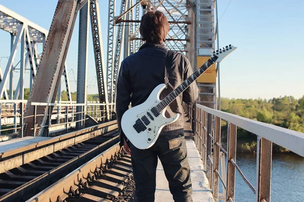 Homem com uma guitarra elétrica na paisagem industrial ao ar livre — Fotografia de Stock