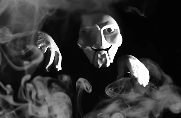Weiße gruselige Maske auf schwarzem Hintergrund mit weißer Hand. — Stockfoto
