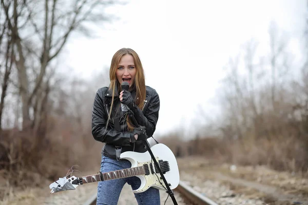 Рок-музыкантка в кожаной куртке с гитарой — стоковое фото