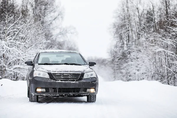 O carro fica em uma estrada coberta de neve — Fotografia de Stock