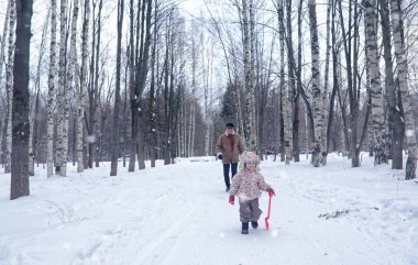 Çocuk kış parkında oynuyor ve ailesiyle eğleniyor.