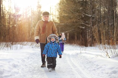 Çocuk kış parkında koşuyor ve ailesiyle eğleniyor.