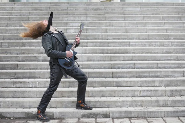 Guitarrista de rock nos degraus. Um músico com uma guitarra baixo em um — Fotografia de Stock