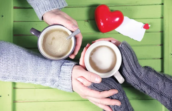 Young couple drinking hot coffee at a wooden table on a date