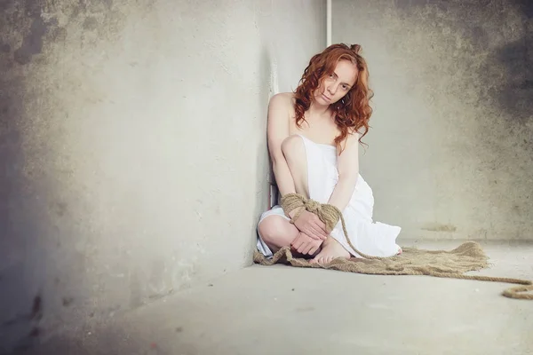 Young girl tied up on the floor. The abducted girl. The victim o — Stock Photo, Image