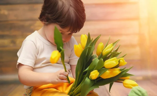 Ein kleines Kind mit einem Strauß gelber Tulpen. ein Junge mit einem Geschenk — Stockfoto