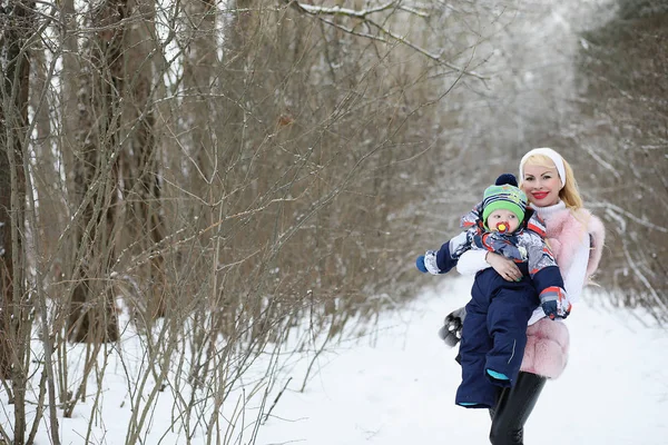 Giovane madre cammina in un giorno d'inverno con un bambino tra le braccia — Foto Stock