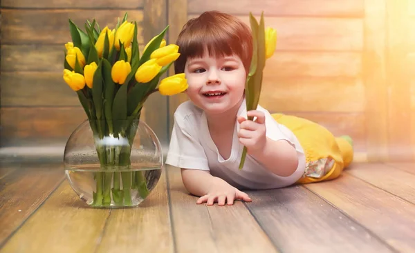 노란색 튤립의 부케와 함께 작은 아이. 선물을 가진 소년 — 스톡 사진