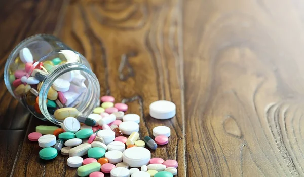 Drogues et pièces de monnaie dans un bocal en verre sur un sol en bois. Économies de poche — Photo
