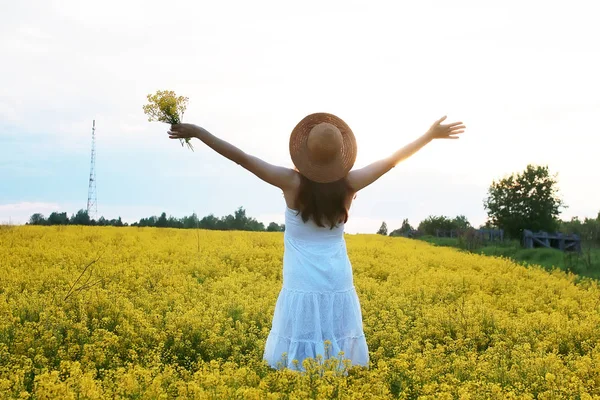Ragazza in cappello di paglia in un campo di fiori gialli in fiore — Foto Stock