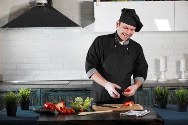 Adam mutfak masasında sebze pişiriyor.