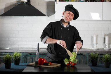 Adam mutfak masasında sebze pişiriyor.