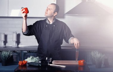 Adam mutfak masasında sebze pişiriyor.