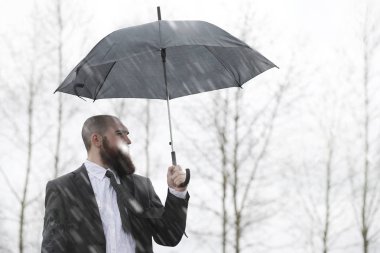 Takım elbiseli kel sakallı bir adam.