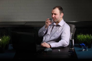 Masada oturan ve dizüstü bilgisayarda çalışan adam