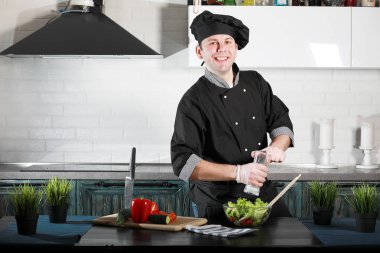 Adam mutfak masasında sebze pişiriyor.