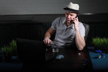 Masada oturan ve dizüstü bilgisayarda çalışan adam