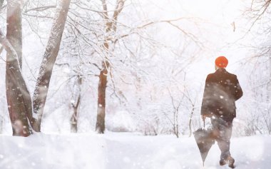 Parkta yürüyen bir adam. Genç adam kışın karla kaplı