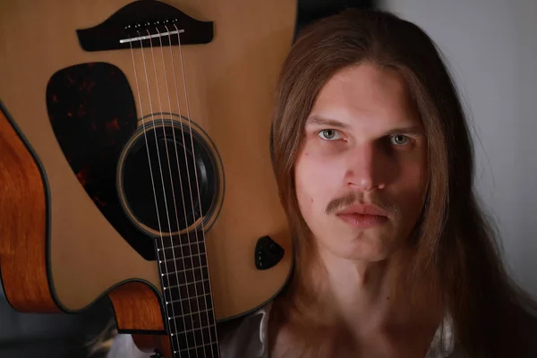 Молодий чоловік з довгим волоссям з гітарою — стокове фото