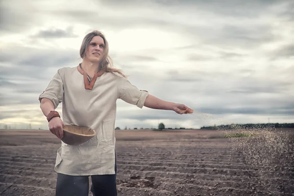 A young peasant sows the field with grain — Stock Photo, Image