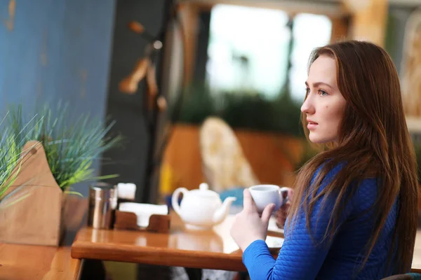 Junges Mädchen sitzt im Café und trinkt Tee — Stockfoto