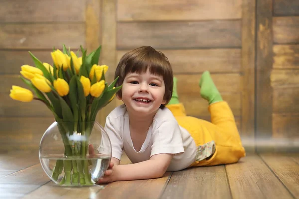 Un niño pequeño con un ramo de tulipanes amarillos. Un chico con un regalo — Foto de Stock