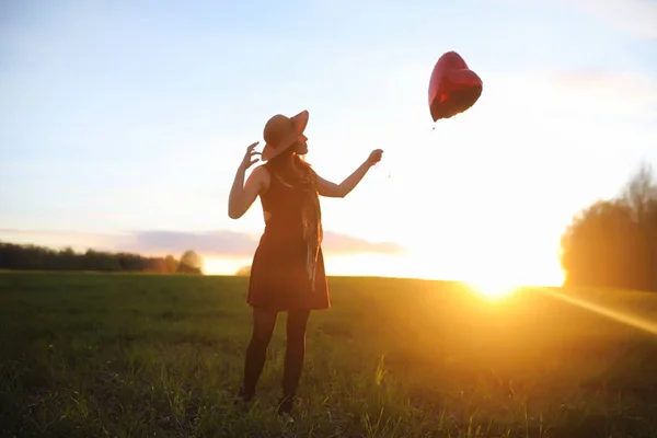 A girl in a hat on a walk in the park. A girl with a basket walks in the spring. Girl is walking along the road at sunset